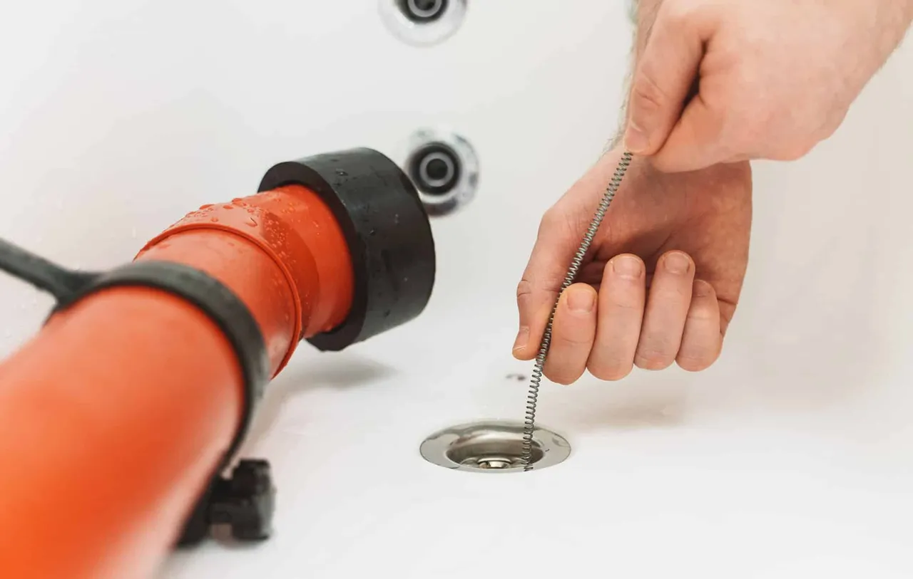 Plumber feeding a drain auger into a bathtub drain