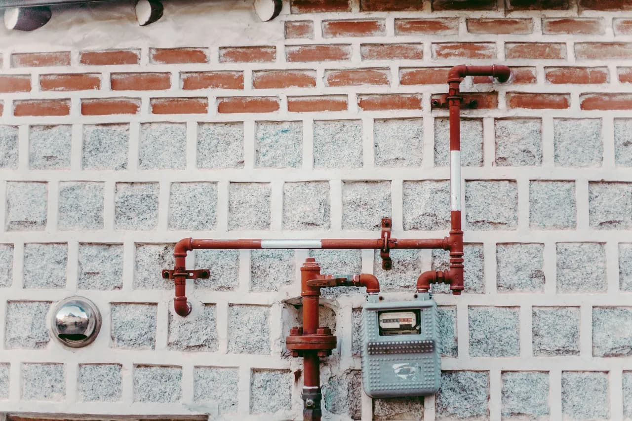 Exterior gas meter and service piping on a masonry wall
